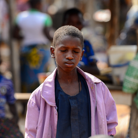 BOHICON, BENIN - JAN 12, 2017: Unidentified Beninese boy in purple jacket closes his eyes at the local market. Benin people suffer of poverty due to the bad economy.のeditorial素材