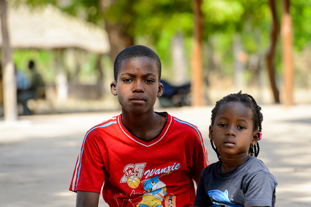 KOUTAMMAKOU, TOGO - JAN 13, 2017: Unidentified Togolese boy in red shirt hugs his little sister in the village. Togo children suffer of poverty due to the bad economy.のeditorial素材