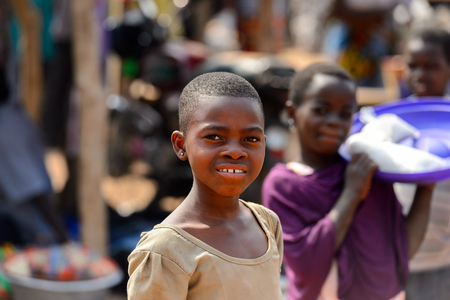BOHICON, BENIN - JAN 12, 2017: Unidentified Beninese girl in mustard dress smiles at the local market. Benin children suffer of poverty due to the bad economy.のeditorial素材
