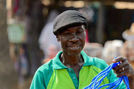 BOHICON, BENIN - JAN 12, 2017: Unidentified Beninese man in green shirt and a cap smiles at the local market. Benin people suffer of poverty due to the bad economy.のeditorial素材