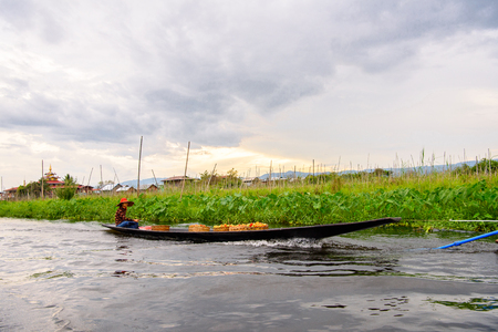 INLE LAKE, MYANMAR - AUG 30, 2016: Unidentified Burmese girl in bamboo boat sails over the Inle Sap,a freshwater lake located in the Nyaungshwe Township of Taunggyi District of Shan State, Myanmarのeditorial素材
