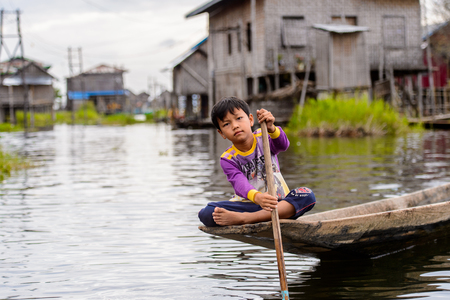 INLE LAKE, MYANMAR - AUG 30, 2016: Unidentified Burmese boy in bamboo boat sails over the Inle Sap,a freshwater lake located in the Nyaungshwe Township of Taunggyi District of Shan State, Myanmarのeditorial素材