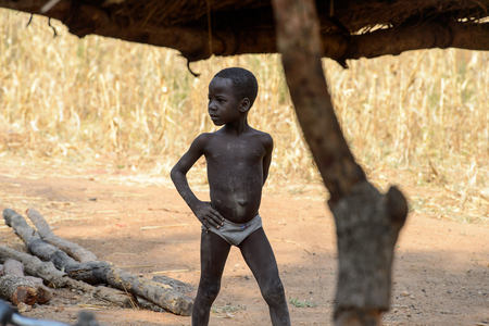 KOUTAMMAKOU, TOGO - JAN 13, 2017: Unidentified Togolese little boy walks in the yard in the village. Togo children suffer of poverty due to the bad economy.のeditorial素材