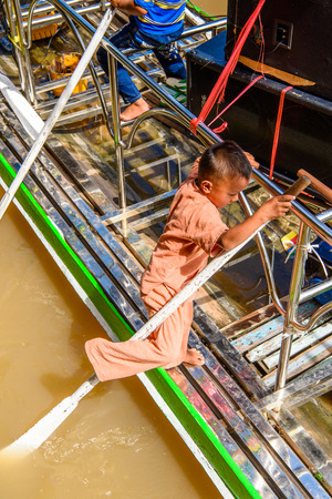 INLE LAKE, MYANMAR - AUG 30, 2016: Unidentified Burmese boy in a wooden boat Inle Lake. 68 per cent of Myanma people belong to Bamar ethnic groupのeditorial素材