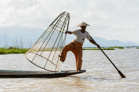 INLE LAKE, MYANMAR - AUG 30, 2016: Unidentified Burmese fisherman on a boat with a special handmade net. This is the traditional way of fishing in Myanmarのeditorial素材