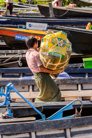 INLE LAKE, MYANMAR - AUG 30, 2016: Unidentified Burmese man carries stuff in bamboo boat over the Inle Sap,a freshwater lake  in the Nyaungshwe Township of Taunggyi District of Shan State, Myanmarのeditorial素材