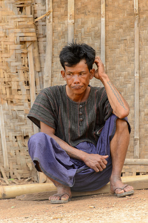 INLE LAKE, MYANMAR - AUG 30, 2016: Unidentified Burmese man sits near a wooden wall. 68 per cent of Myanma people belong to Bamar ethnic groupのeditorial素材