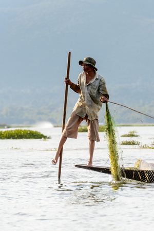 INLE LAKE, MYANMAR - AUG 30, 2016: Unidentified Burmese fisherman on a boat with a special handmade net. This is the traditional way of fishing in Myanmarのeditorial素材