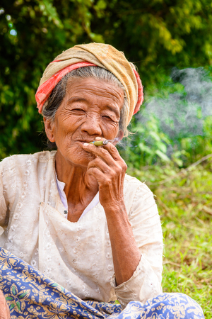 INLE LAKE, MYANMAR - AUG 30, 2016: Unidentified Burmese old lade smoke a cigarette. 68 per cent of Myanma people belong to Bamar ethnic groupのeditorial素材