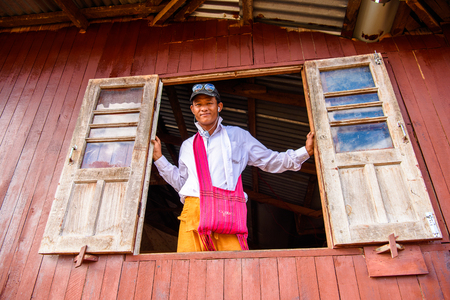 INLE LAKE, MYANMAR - AUG 30, 2016: Unidentified Burmese man open a window, Inle lake. 68 per cent of Myanma people belong to Bamar ethnic groupのeditorial素材