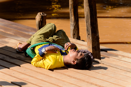 INLE LAKE, MYANMAR - AUG 30, 2016: Unidentified Burmese boy sleeps on a pier. 68 per cent of Myanma people belong to Bamar ethnic groupのeditorial素材