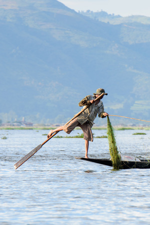 INLE LAKE, MYANMAR - AUG 30, 2016: Unidentified Burmese fisherman on a boat with a special handmade net. This is the traditional way of fishing in Myanmarのeditorial素材