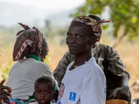 KOUTAMMAKOU, TOGO - JAN 13, 2017: Unidentified Togolese woman looks ahead with a baby nearby in the village. Togo people suffer of poverty due to the bad economy.のeditorial素材