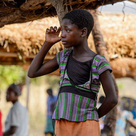 KOUTAMMAKOU, TOGO - JAN 13, 2017: Unidentified Togolese  young woman stands near the canopy in the village. Togo people suffer of poverty due to the bad economy.のeditorial素材