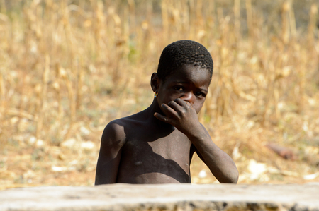 KOUTAMMAKOU, TOGO - JAN 13, 2017: Unidentified Togolese little girl touches her nose in the village. Togo children suffer of poverty due to the bad economy.のeditorial素材