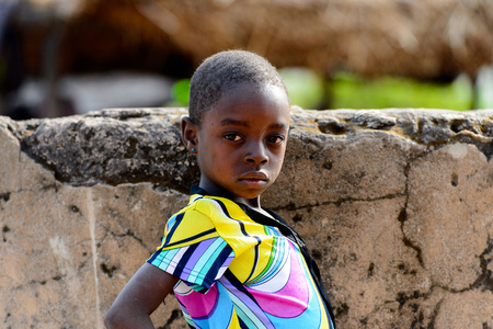 KOUTAMMAKOU, TOGO - JAN 13, 2017: Unidentified Togolese little girl in colored shirt stands near the well in the village. Togo children suffer of poverty due to the bad economy.のeditorial素材
