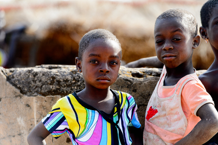 KOUTAMMAKOU, TOGO - JAN 13, 2017: Unidentified Togolese little children in colored shirts stand behind the well in the village. Togo children suffer of poverty due to the bad economy.のeditorial素材