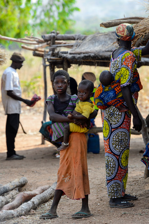 KOUTAMMAKOU, TOGO - JAN 13, 2017: Unidentified Togolese  girl carries a baby in the village. Togo people suffer of poverty due to the bad economy.のeditorial素材