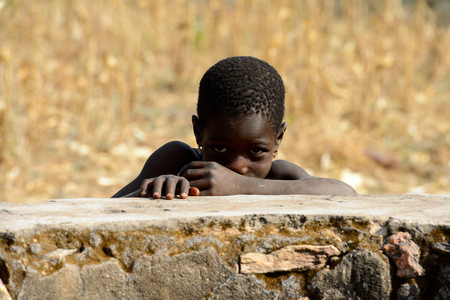 KOUTAMMAKOU, TOGO - JAN 13, 2017: Unidentified Togolese little girl touches her nose in the village. Togo children suffer of poverty due to the bad economy.のeditorial素材