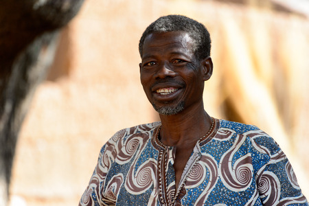KARA REG., TOGO - JAN 14, 2017: Unidentified Konkomba old man in colored shirt looks ahead in the...