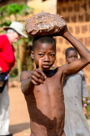 KARA REG., TOGO - JAN 14, 2017: Unidentified Konkomba little boy holds a rock on his head in the village. Konkombas are ethnic group of Togoのeditorial素材