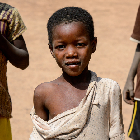 KARA REG., TOGO - JAN 14, 2017: Unidentified Konkomba little boy in torned shirt looks ahead in the village. Konkombas are ethnic group of Togoのeditorial素材
