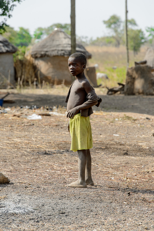 GHANI, GHANA - JAN 14, 2017: Unidentified Ghanaian boy in green shorts looks away in the Ghani village. Ghana children suffer of poverty due to the bad economy.のeditorial素材