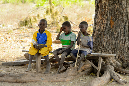 GHANI, GHANA - JAN 14, 2017: Unidentified Ghanaian children sit on the wooden bench in the Ghani village. Ghana children suffer of poverty due to the bad economy.のeditorial素材