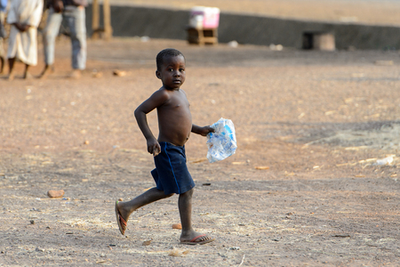 DAGOMBA VILLAGE, GHANA - JAN 14, 2017: Unidentified Dagomban little boy walks with a plastic bag in the local village. Dagombas are ethnic group of Northern Ghanaのeditorial素材