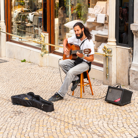 LISBON, PORTUGAL - JUN 20, 2014:  Unidentified man makes music on the touristic street in Lisbon, Portugal. Lisbon is the westernmost large city Europe and the seventh-most-visited city in Southern Europeのeditorial素材