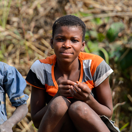 BRONG AHAFO, GHANA - JAN 15, 2017: Unidentified Ghanaian woman in colored shirt sits on the ground. Ghana people suffer of poverty due to the bad economy.のeditorial素材