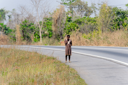 BRONG AHAFO, GHANA - JAN 15, 2017: Unidentified Ghanaian woman stands on the road. Ghana people suffer of poverty due to the bad economy.のeditorial素材