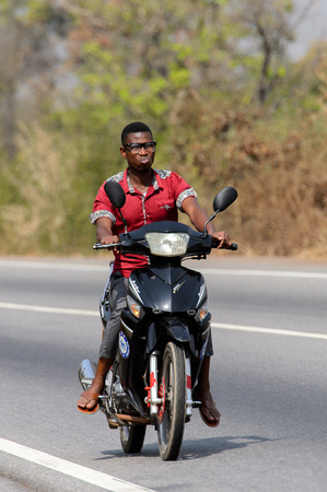 BRONG AHAFO, GHANA - JAN 15, 2017: Unidentified Ghanaian man in helmet rides a motorcycle. Ghana people suffer of poverty due to the bad economy.のeditorial素材