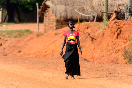 TECHIMAN, GHANA - JAN 15, 2017: Unidentified Ashanti woman in black skirt walks along the road in the local village. Ashante are ethnic group of Ghanaのeditorial素材