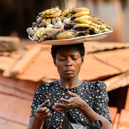 BOABENG, GHANA - JAN 15, 2017: Unidentified Ghanaian woman carries a basin on her head in the local village. Ghana people suffer of poverty due to the bad economy.のeditorial素材