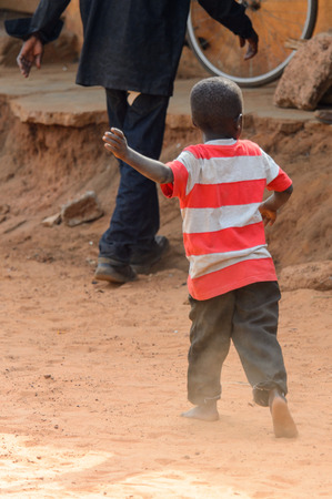 TECHIMAN, GHANA - JAN 15, 2017: Unidentified Ashanti boy in white and red shirt walks in the local village. Ashante are ethnic group of Ghanaのeditorial素材