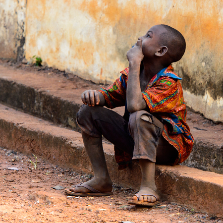 BOABENG, GHANA - JAN 15, 2017: Unidentified Ghanaian boy sits on the stair and looks up in the local...