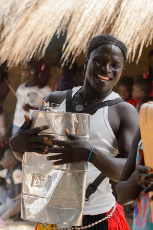 ORANGO ISL., GUINEA BISSAU - MAY 3, 2017: Unidentified local Man knocks on canister and smiles  during Vaca Bruto, traditional Mask danceのeditorial素材
