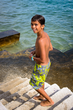 DALMATIA, REGION OF SPLIT, CROATIA - AUG 20, 2014: Unidentified boy at the Adriatic coast. Coast of the Adriatic Sea in Dalmatia became a popular destination for millions of touristsのeditorial素材