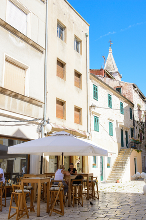 SIBENIK, CROATIA - AUG 26, 2014: Unidentified tourists in a small street restaurant tables in Sibenic, Croatia. Sibenic is a popular touristic destination in Croatiaのeditorial素材