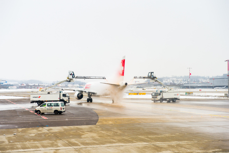 ZURICH, SWITZERLAND - JAN 26, 2015: Plane of the Swiss International Air Lines is treated by the anti freezing liquid in the Zurich Kloten Airport, the largest international airport of Switzerlandのeditorial素材