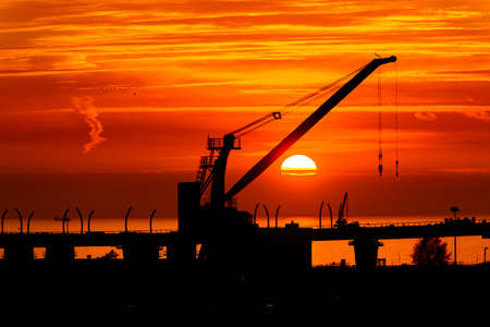Construction cranes on the Sunset over the sea in Russiaの写真素材
