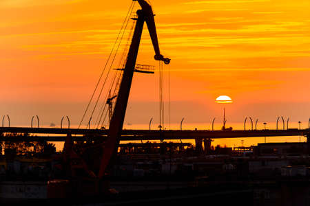 Construction cranes on the Sunset over the sea in Russiaの写真素材