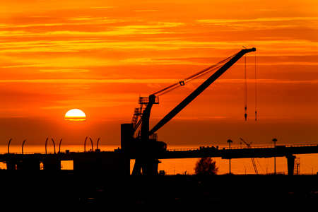 Construction cranes on the Sunset over the sea in Russiaの写真素材
