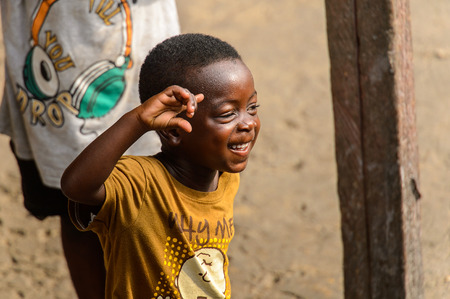 ACCRA, GHANA - JAN 8, 2017: Unidentified Ghanaian little boy in mustard shirt smiles on the street. Children of Ghana suffer of poverty due to the economic situationのeditorial素材