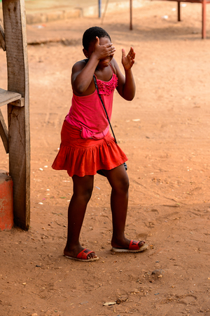 ACCRA, GHANA - JAN 8, 2017: Unidentified Ghanaian woman in red dress closes her face with her hand. People of Ghana suffer of poverty due to the economic situationのeditorial素材