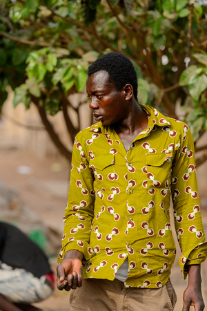 ACCRA, GHANA - JAN 8, 2017: Unidentified Ghanaian man in green shirt stand on the street. People of Ghana suffer of poverty due to the economic situationのeditorial素材