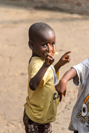 ACCRA, GHANA - JAN 8, 2017: Unidentified Ghanaian little boy in mustard shirt shows his fingers. Children of Ghana suffer of poverty due to the economic situationのeditorial素材