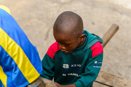 ACCRA, GHANA - JAN 8, 2017: Unidentified Ghanaian boy in celabon sweater holds on the wooden cart. Children of Ghana suffer of poverty due to the economic situationのeditorial素材