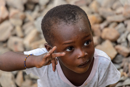 ACCRA, GHANA - JAN 8, 2017: Unidentified Ghanaian beautiful little girl in white shirt shows her fingers. Children of Ghana suffer of poverty due to the economic situationのeditorial素材